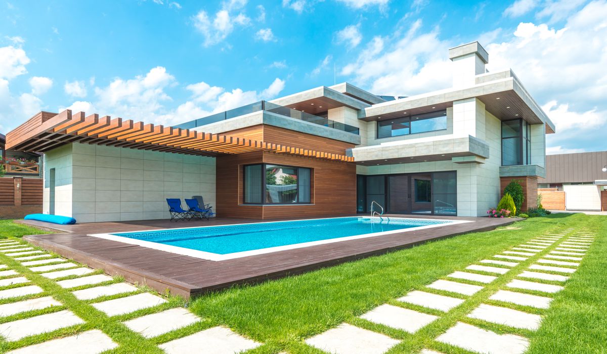Modern residential in-ground pool construction with wooden deck and landscaping